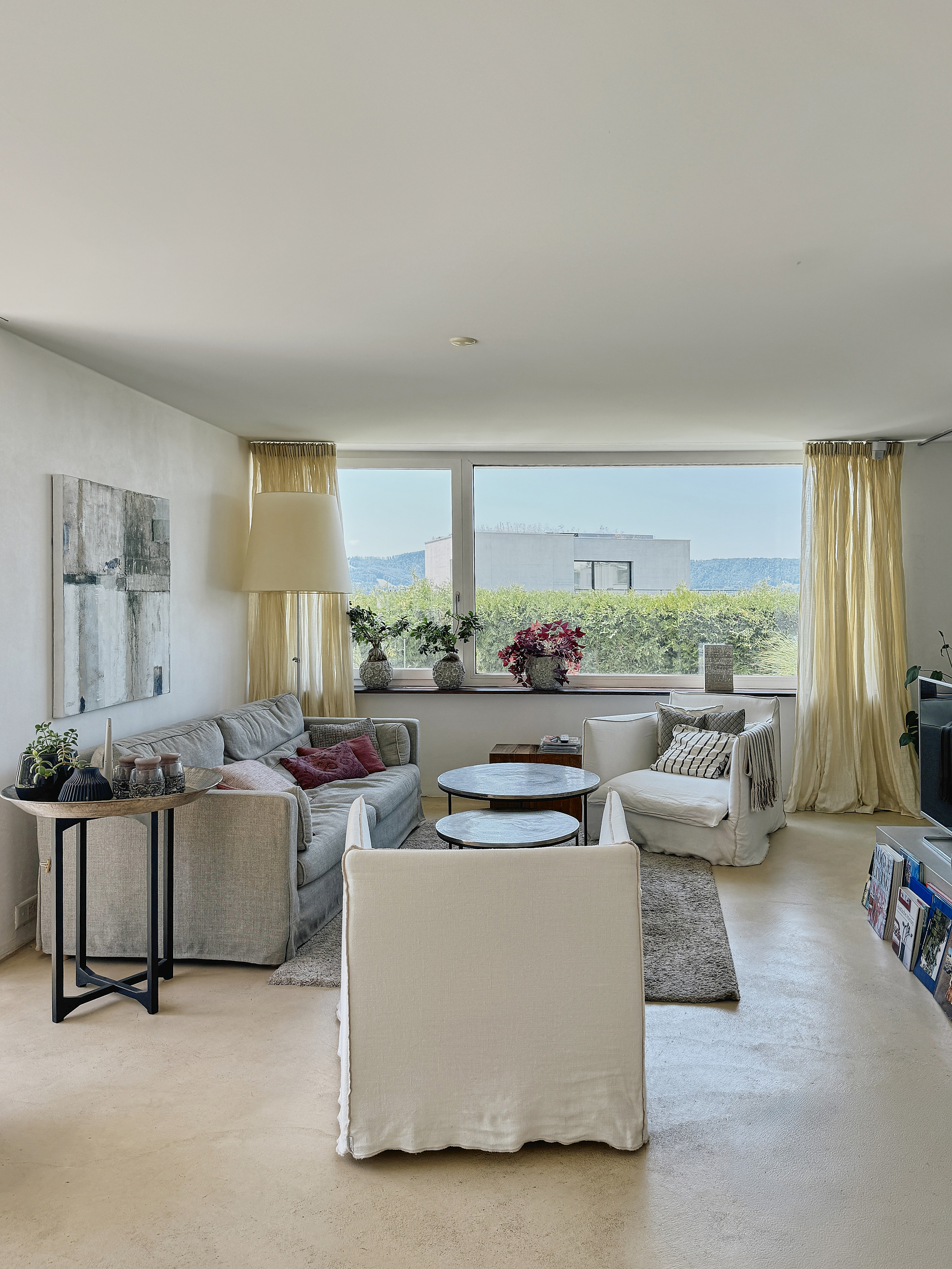 Light-filled and open spaced living room with white sofas and wide window.